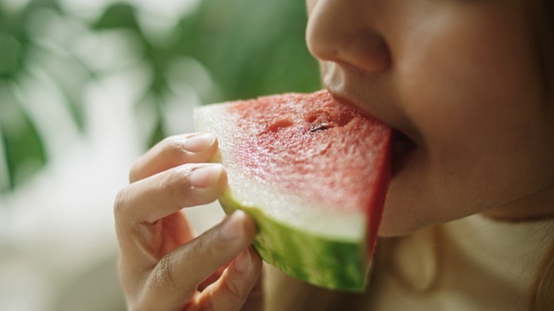 a person takes a bite out of a watermelon slice