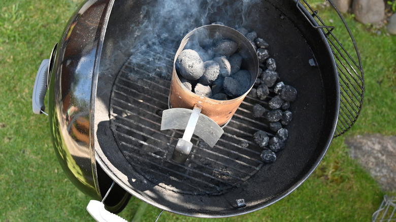 A chimney starter on a backyard charcoal grill