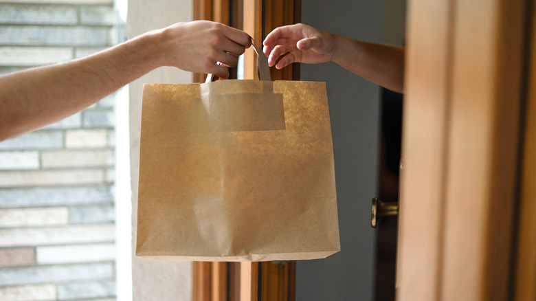 A person delivering food in a brown paper bag