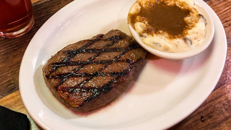 A Texas Roadhouse steak and mashed potatoes served on a white plate
