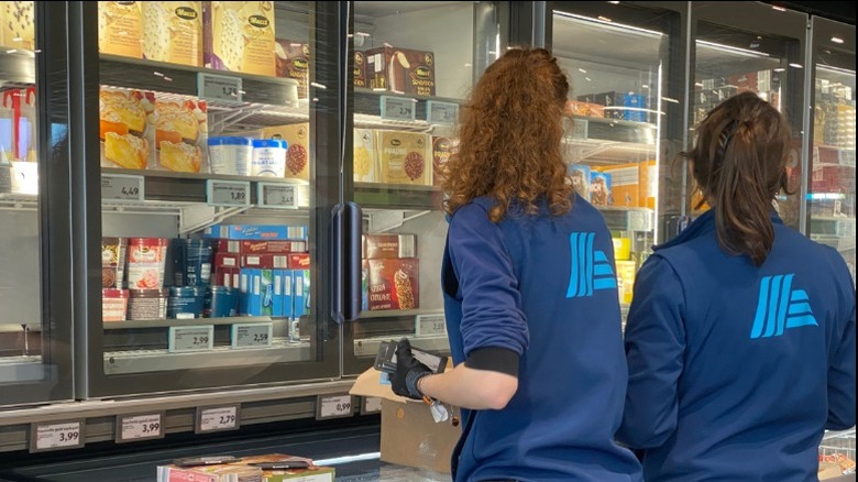 Two female Aldi employees stock frozen food items