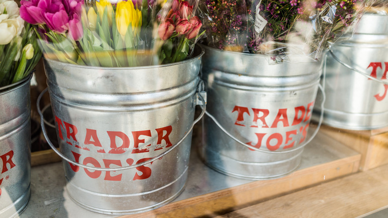 Buckets of Trader Joe's flowers arranged on wooden shelving