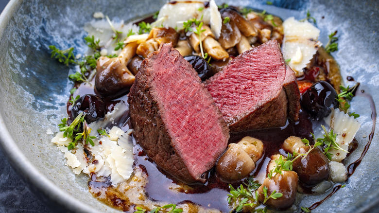 Sliced venison steak on a plate with side veggies