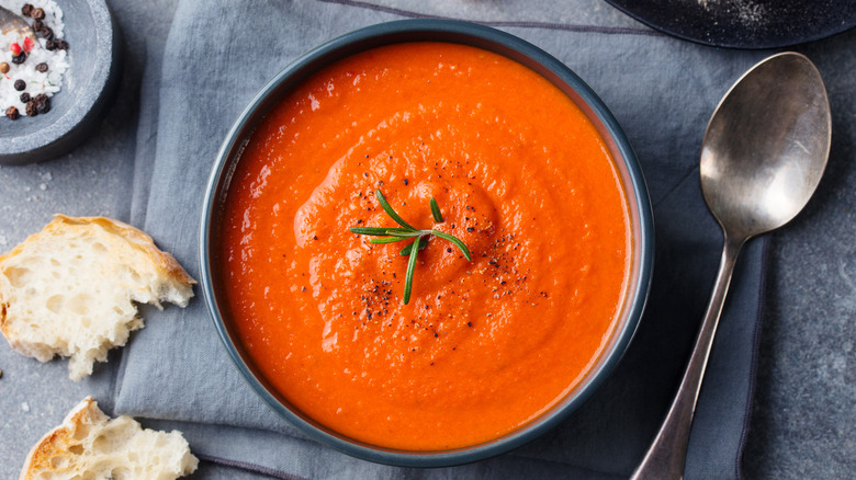 Top view of tomato soup with rosemary garnish