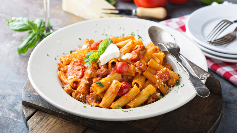 A plate of rigatoni Bolognese with fresh herbs and cheese