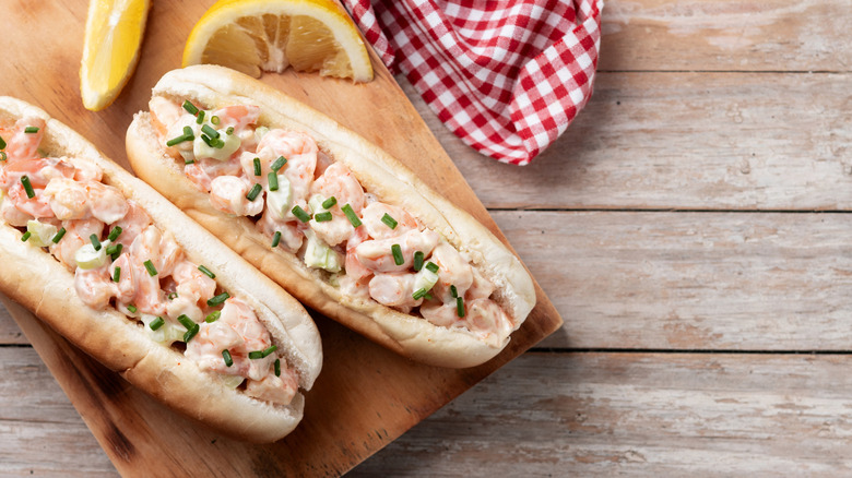 buns filled with seafood salad on cutting board with lemon slices