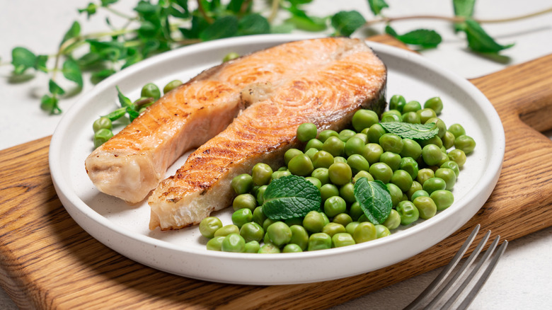 Salmon steak and peas with mint on white plate