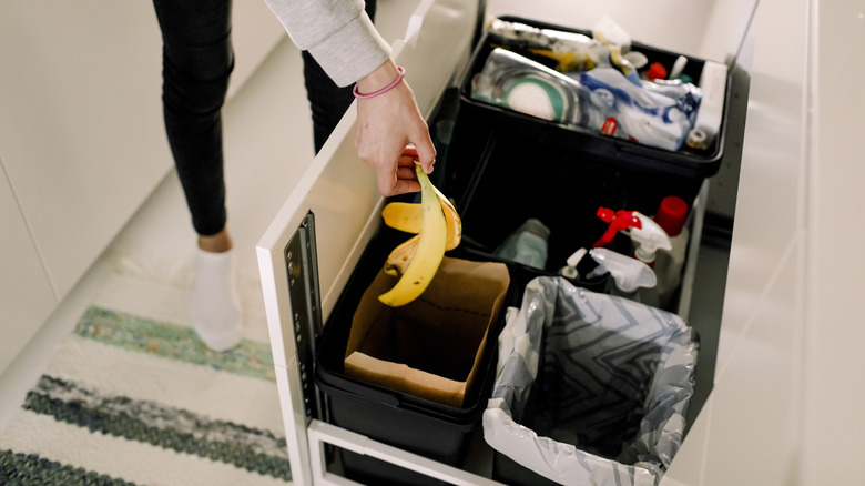 A person throwing away a banana peel