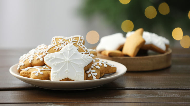 Two plates of designed holiday cookies on a wooden table.