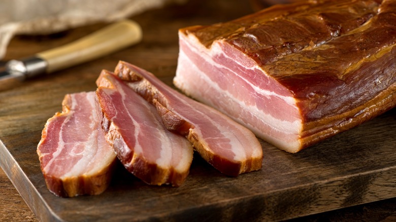 Whole smoked bacon slab on wood cutting board