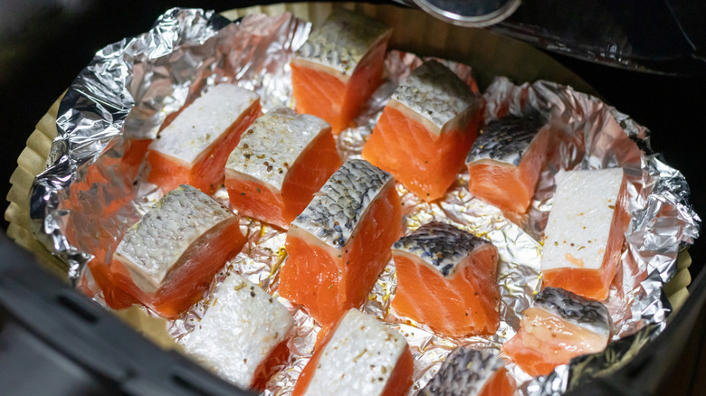 Raw salmon pieces on foil-lined air fryer basket