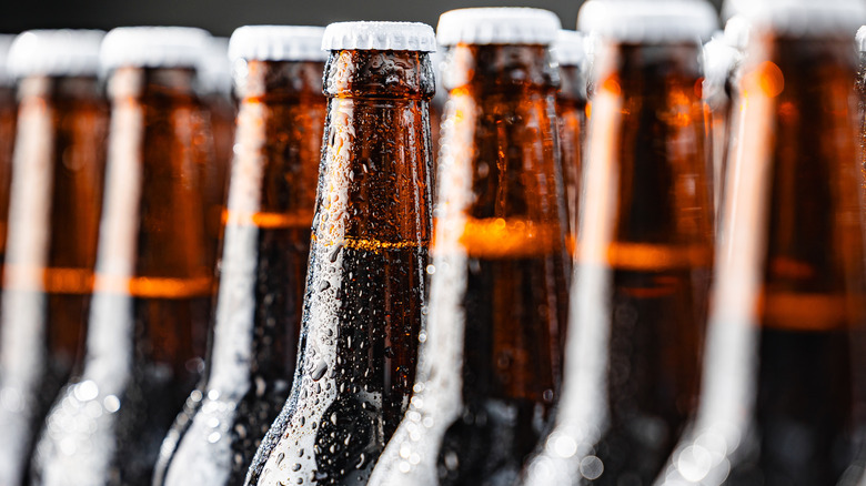 Several ice cold beer bottles with condensation dripping off of them