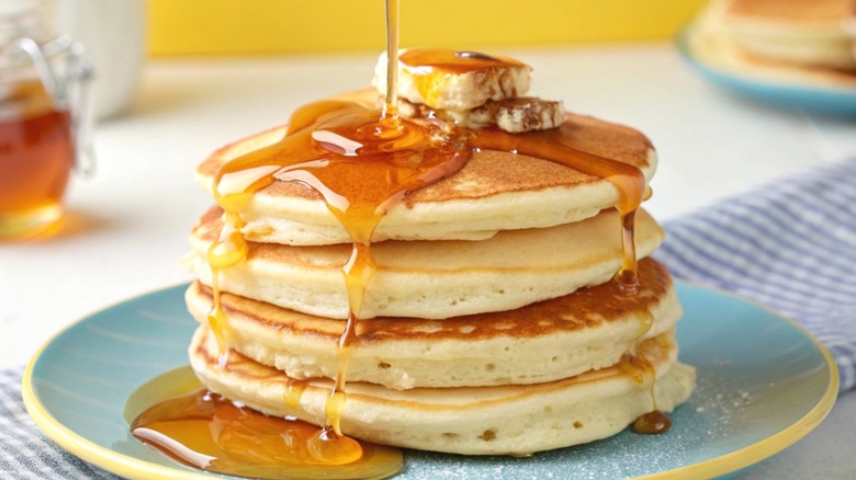 A tall stack of panckes, drizzled with maple syrup.