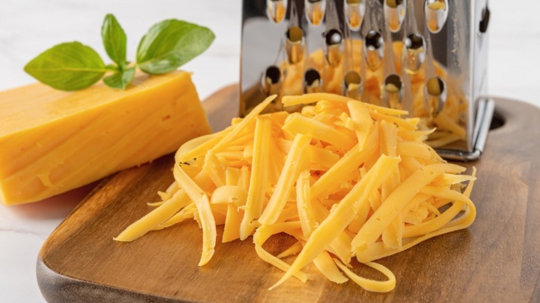 Shredded cheddar next to a cheese grater