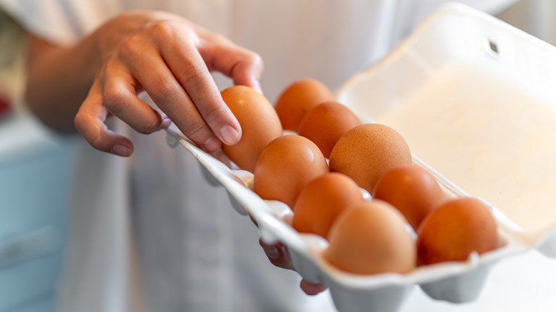 A person picking up eggs from an egg carton.