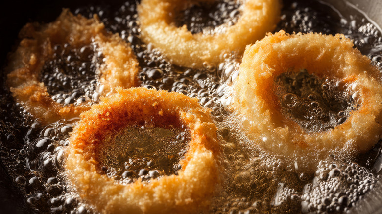 Four onion rings frying in hot oil