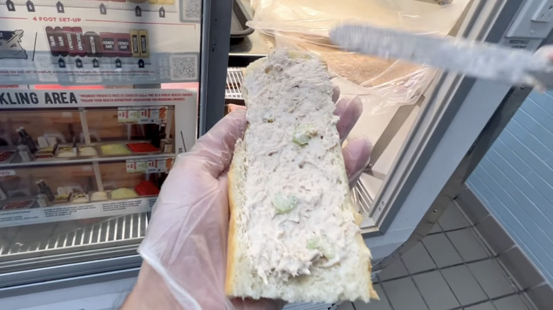 hands making tuna sub sandwich