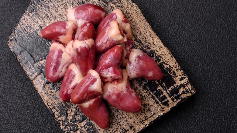 Raw chicken hearts on a dark concrete background