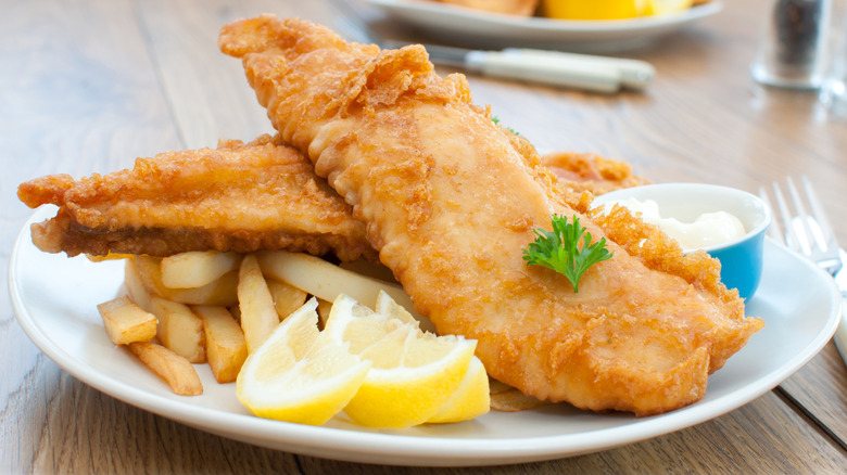 Plate of fried fish fillets, fries, and lemon wedges