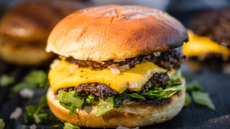 A double smash burger on a bun with cheese, onions, and lettuce