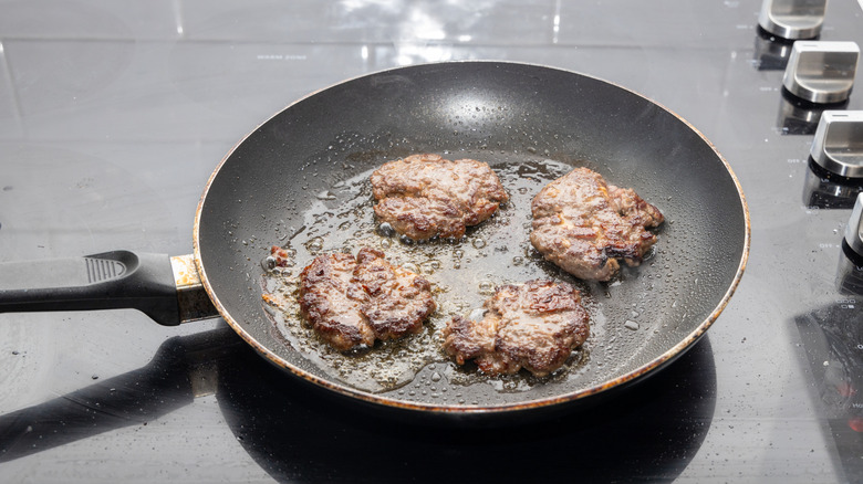 Burgers cooking in a nonstick pan.