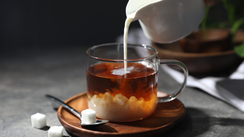 cream is poured into glass cup with black tea and sugar