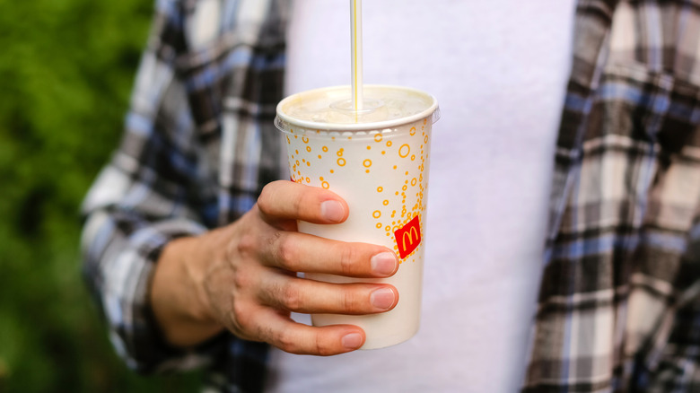 A person holds a McDonald's cold cup with a straw