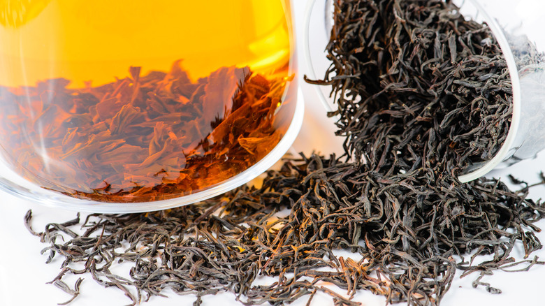 Dried orange pekoe whole tea leaves steep in a glass mug