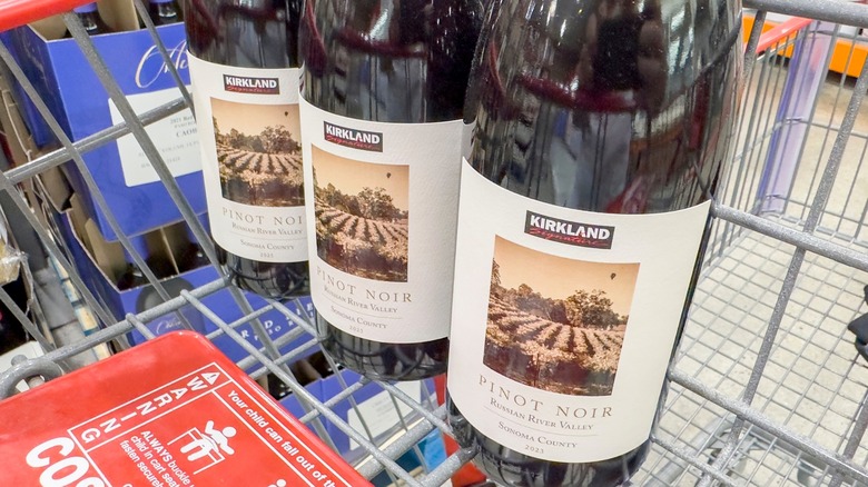 Three bottles of Kirkland Signature pinot noir wine in shopping cart