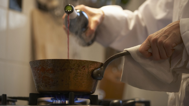chef pouring wine into pot