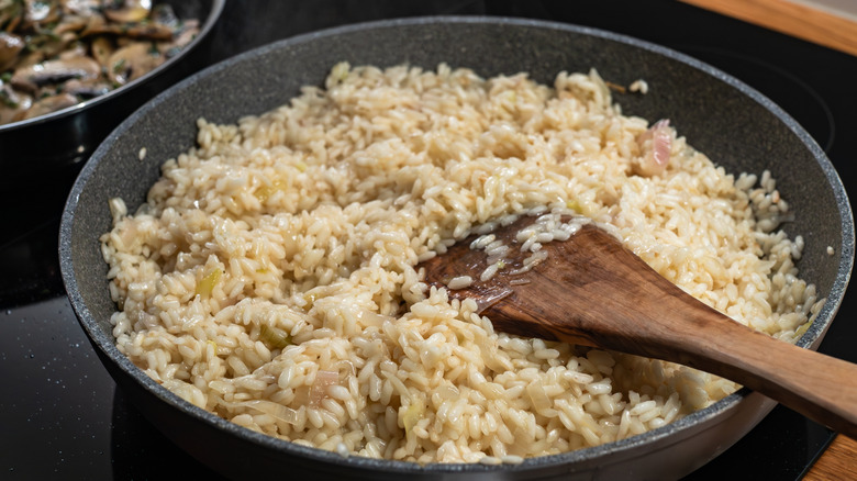 Risotto cooking on stovetop with wooden spatula in the rice