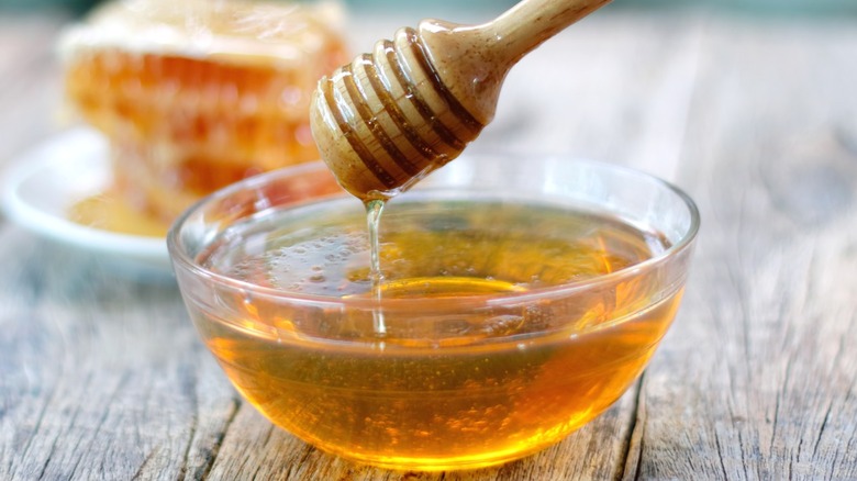 A bowl of honey with dipper and honeycomb
