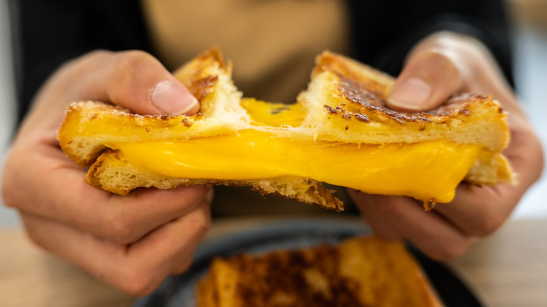A person pulling apart a grilled cheese sandwich.