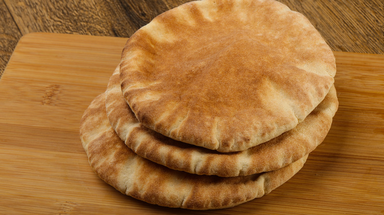 A heap of pita breads on a wooden board