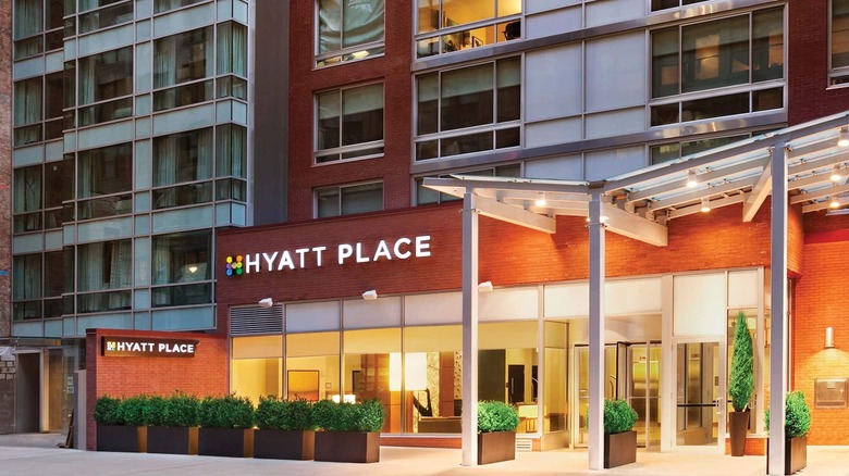 The entrance to a Hyatt Place from a city block with plenty of light and greenery.