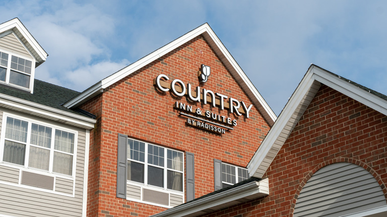 A white Country Inn & Suites by Radisson sign on the exterior of a brick hotel.