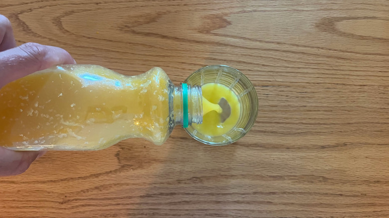 Hand pouring orange juice into a glass