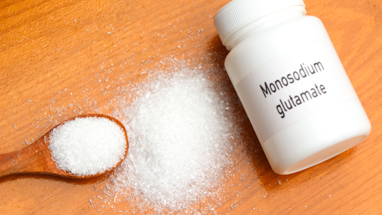 a bottle of monosodium glutamate also known as MSG next to a spoonful of it.