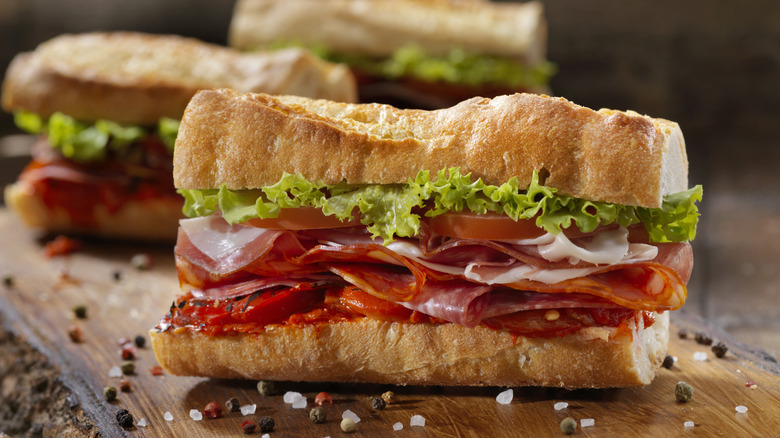 An Italian sub on a six-inch hoagie-style roll on a wooden cutting board