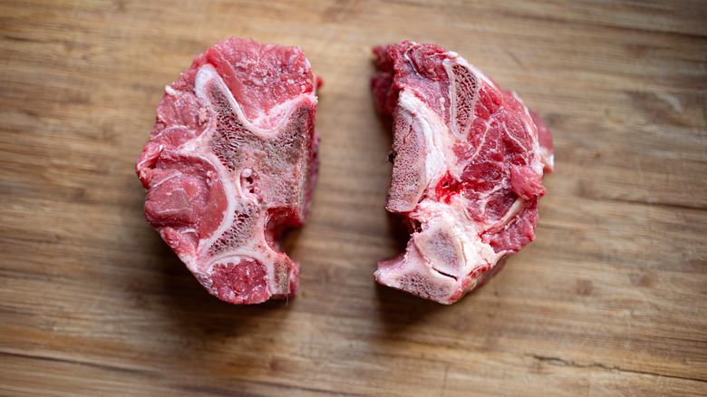 Two raw pieces of neck beef on a wooden table