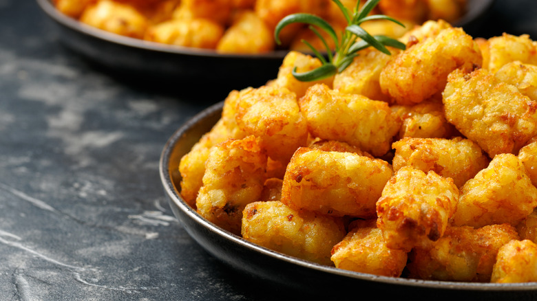 Cooked tater tots on a black plate