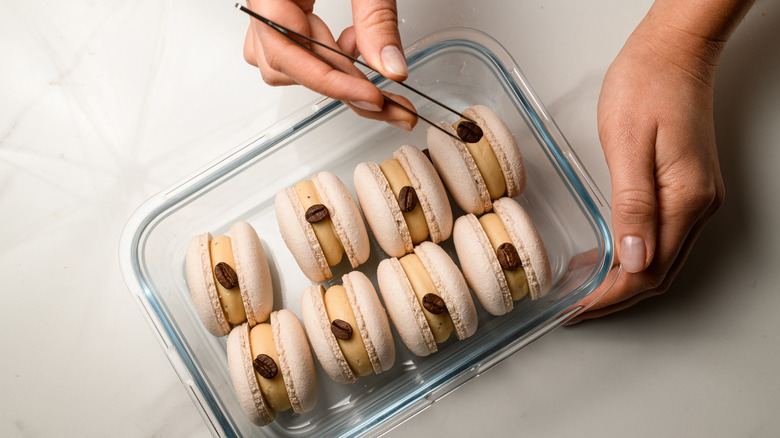 A baker using tweezers to decorate macarons