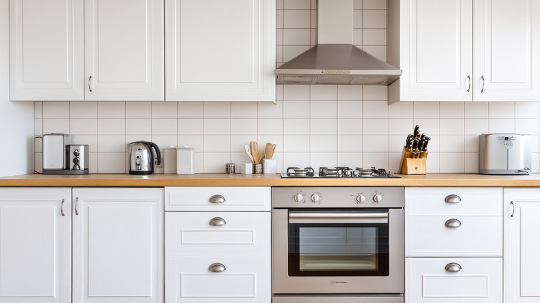A modern home kitchen with oven in view and white cabinetry