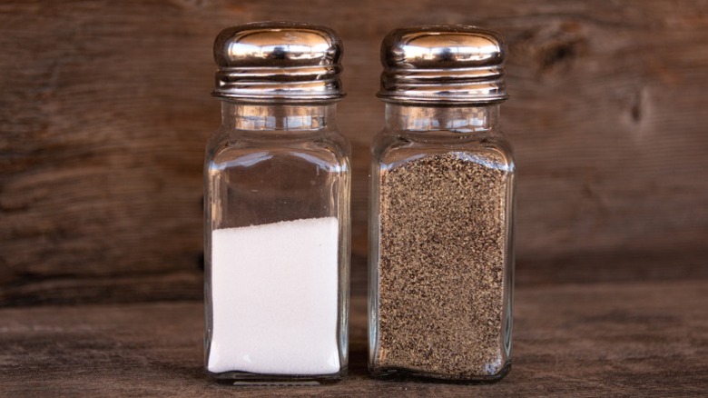 Salt and pepper shakers side by side against a wooden background