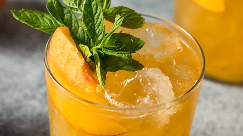 Bourbon smash with fresh peach and mint sprig for garnish.