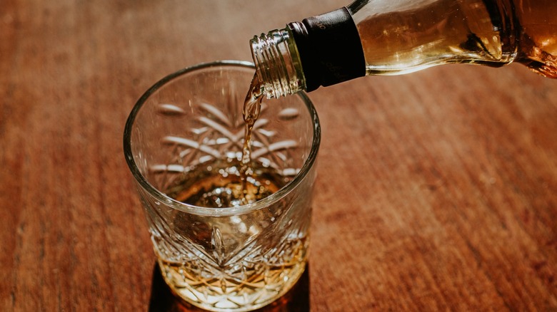 Whiskey is poured into a rocks glass.