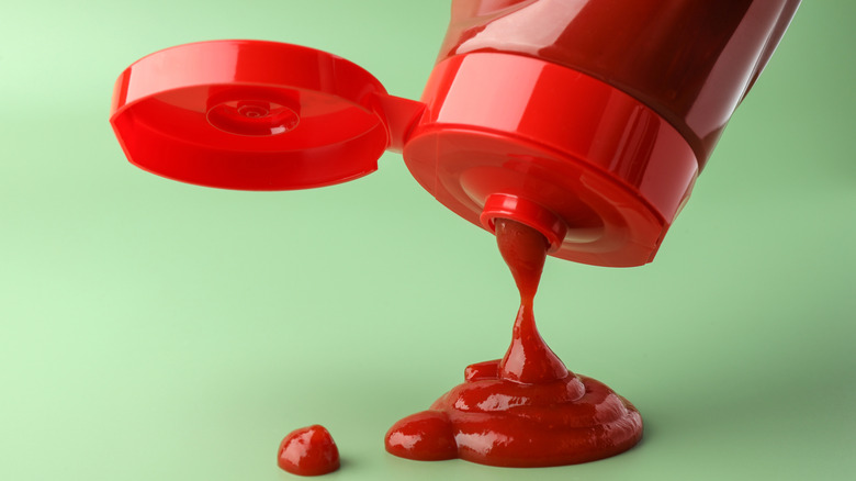 Red bottle squeezing ketchup onto a green surface