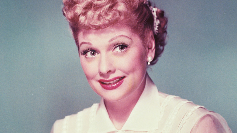Lucille Ball smiles in a white blouse for a studio portrait