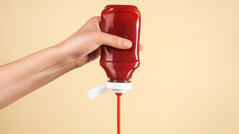 A person squeezes ketchup out of a plastic bottle