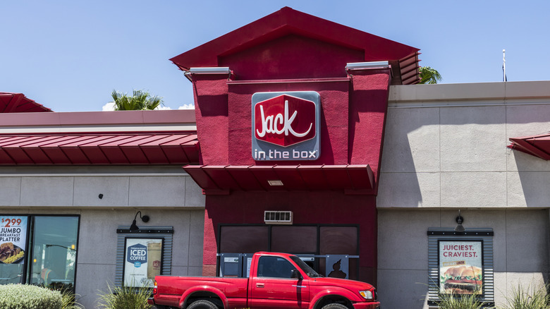 Exterior of a Jack in the Box location, with a red pickup truck parked at the drive-thru window
